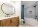 Bathroom featuring a wooden vanity with a round mirror and a bathtub with blue curtain at 263 Ohm Ave, Avondale Estates, GA 30002