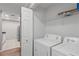 Bright laundry room features a full-size white washer and dryer and overhead shelving for storage at 3655 Habersham Ne Rd # 215, Atlanta, GA 30305