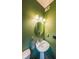 Powder room with green walls, pedestal sink, round mirror and three-bulb vanity light at 4118 Kentmere Main Nw, Kennesaw, GA 30144