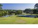 Aerial view of blue and green tennis courts next to a pond, gazebo, green grass, and many trees at 47 Monet Nw Ct, Atlanta, GA 30327
