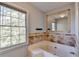 A tiled bathtub is situated next to a large window with a view of the trees outside at 1450 Pinyon Pl, Lawrenceville, GA 30043