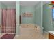 Bathroom boasting a garden tub, a shower with light pink curtains, and a window for natural light at 251 Bent Creek Dr, Dallas, GA 30157