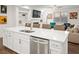 Kitchen island with stainless dishwasher, light countertop, sink, and view into the living room at 2855 Mcmurtry St, Cumming, GA 30041