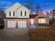 Charming two-story home at dusk with a brick and vinyl exterior and manicured lawn at 6920 Greenfield Ln, Cumming, GA 30028