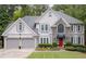 Charming two-story home features a manicured lawn, gray siding, stone accents, and a two-car garage at 3202 Eagle Watch Dr, Woodstock, GA 30189