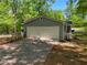 Attached two-car garage with white door and concrete driveway, surrounded by mature trees at 411 Buckingham Cir, Marietta, GA 30066