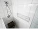 Close up of a modern shower with mosaic tile niche, marble tile, wood stool, and a rainfall showerhead at 411 Buckingham Cir, Marietta, GA 30066