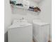 Bright laundry room with white appliances, open shelving and white walls at 13699 Inman Rd, Hampton, GA 30228