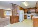 View of kitchen with wooden cabinets, white appliances, and window to carpeted living room at 166 Muse Rd, Fayetteville, GA 30214