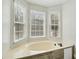Bright bathroom with a soaking tub nestled in front of three windows offering a view to the outdoors at 122 Belmonte Sw Dr, Atlanta, GA 30311