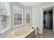 Bright bathroom with a large soaking tub in front of bay windows, and a glimpse of a beautifully tiled shower at 122 Belmonte Sw Dr, Atlanta, GA 30311