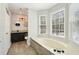 A bright bathroom with a large soaking tub, vanity with round mirrors, and a glimpse of a tiled shower at 122 Belmonte Sw Dr, Atlanta, GA 30311