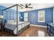 Stylish bedroom with blue walls, wood floors, a canopy bed, and a ceiling fan with a light fixture at 122 Belmonte Sw Dr, Atlanta, GA 30311