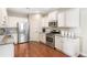 White kitchen with stainless steel appliances, granite counters, and hardwood floors at 1874 Manor View Nw Cir # 4, Acworth, GA 30101