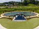 Aerial view of an amphitheater with a stage, a water feature and grassy seating surrounded by lush greenery at 2515 Little John Ct, Cumming, GA 30040