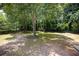 Large, partially shaded backyard with mature trees and plenty of space for outdoor activities with a wood fence at 2515 Little John Ct, Cumming, GA 30040