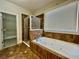 Bathroom featuring tiled shower and tub surround, garden tub and a glass door to a carpeted closet at 2822 Salem Oak Way, Duluth, GA 30096