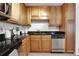 A view of the kitchen sink, dishwasher and range with tan colored cabinets and black counter tops at 1468 Briarwood Ne Rd # 502, Brookhaven, GA 30319