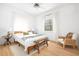 Bright bedroom with a wooden bed frame, hardwood floors, white curtains, and a cozy chair at 218 Garland Ave, Decatur, GA 30030