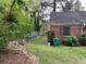 A fenced yard with green space, bordering a modest red brick house with lush landscaping at 3095 Rainbow Dr, Decatur, GA 30034