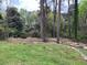 View of the property's spacious backyard surrounded by mature trees and wood at 3095 Rainbow Dr, Decatur, GA 30034