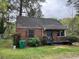 Quaint brick home with a compact front yard and black framed windows, surrounded by mature trees at 3095 Rainbow Dr, Decatur, GA 30034