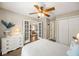 Cozy bedroom features a ceiling fan, hardwood floors, a white dresser, and double french doors at 302 Roswell Green Ln, Roswell, GA 30075