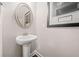 Elegant half bathroom featuring a classic pedestal sink with an oval mirror and stylish decor at 6441 Oakhurst Pl, Fairburn, GA 30213