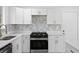 Modern kitchen showcasing white cabinets, stylish backsplash, and stainless steel appliances at 8212 Englewood Trl, Riverdale, GA 30274