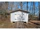 A bright, white storage shed with a wooden ramp is nestled among trees in the backyard at 1129 Annie Sw Ln, Mableton, GA 30126