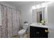 Well-lit bathroom with a shower, decorative floral shower curtain, and sleek vanity at 1417 Hickory Sw Dr, Lilburn, GA 30047