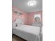 Bright bedroom with pink walls, a white bed frame, and a decorative mirror at 1417 Hickory Sw Dr, Lilburn, GA 30047