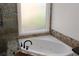 Corner bathtub with decorative tile and gold fixtures at 2335 Corbett Ct, Powder Springs, GA 30127