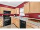 A well-lit kitchen featuring light wood cabinets, a black oven and microwave, and red walls at 2411 Heritage Park Nw Cir # 14, Kennesaw, GA 30144