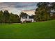 Dusk view of the white two-story home from the expansive backyard with walkout deck and mature trees at 5077 Fieldview Dr, Douglasville, GA 30135