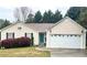 Charming one story home with a lush green lawn and a bright teal front door and a two car garage at 413 Remington Ct, Villa Rica, GA 30180