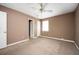 This bedroom features neutral paint, a light-colored carpet, ceiling fan, and bright light from the window and hallway access at 6347 Steepleridge Ct, Riverdale, GA 30296