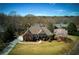 Aerial shot of a beautiful brick house with lush green lawn, mature trees, and a long driveway at 8005 Sweet Creek Rd, Johns Creek, GA 30097