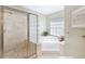 Modern bathroom featuring a glass-enclosed shower, soaking tub, and a bright window, creating a relaxing atmosphere at 8005 Sweet Creek Rd, Johns Creek, GA 30097