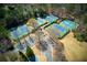 Aerial view of four well-maintained tennis courts surrounded by lush greenery and a parking area at 8005 Sweet Creek Rd, Johns Creek, GA 30097