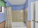 A well-lit bathroom showcasing a clean white tub and shower with blue walls and a patterned shower curtain at 5221 La Paloma Sw Dr, Lilburn, GA 30047