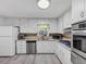 Updated kitchen featuring stainless appliances, white cabinetry, and light plank flooring at 5221 La Paloma Sw Dr, Lilburn, GA 30047
