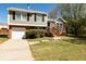 Charming two-story home featuring a brick facade, attached garage, landscaped yard, and inviting stairway to the front door at 6136 Marbut Rd, Lithonia, GA 30058