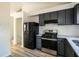 Bright kitchen featuring dark cabinets, stainless steel appliances, granite countertops, and a white tile backsplash at 6136 Marbut Rd, Lithonia, GA 30058