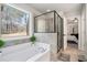 Bright bathroom featuring a soaking tub, glass enclosed shower, and a large window at 2320 Ridge View Dr, Loganville, GA 30052