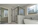 Bright bathroom with soaking tub, glass shower, tile surround, and scenic window at 4850 Cool Springs Rd, Winston, GA 30187