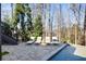 Backyard pool and lounge area with stone pavers, trees, and staircase access at 230 Hardscrabble Rd, Roswell, GA 30075