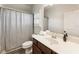 Well-lit bathroom featuring a vanity with a sink, a toilet, and a shower with a striped curtain at 230 Hardscrabble Rd, Roswell, GA 30075