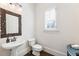 Charming powder room with pedestal sink, ornate mirror, and window with shutter, creating a cozy and inviting space at 230 Hardscrabble Rd, Roswell, GA 30075