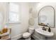 Charming powder room with stylish mirror, decorative wall hangings, and wood accents at 230 Hardscrabble Rd, Roswell, GA 30075